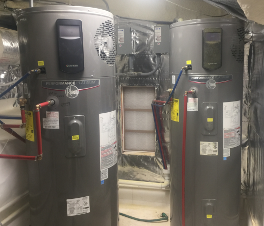 80-gallon Rheem hybrid water heaters. The shows two tall, cylindrical water heaters with pipes connected to them.