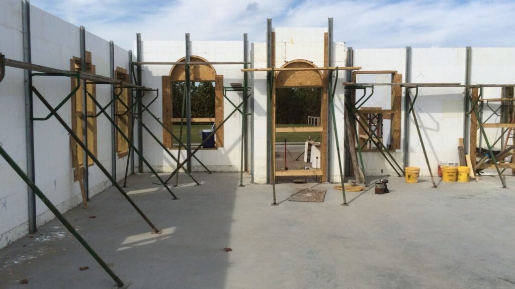 The concrete base of a house surrounded by Insulated Concrete Forms (ICF). There is bare concrete held up by wood.