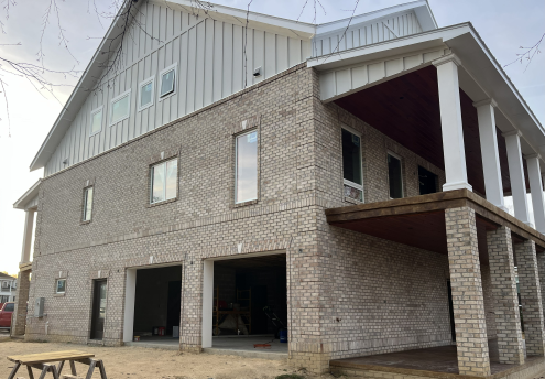 A large, in-progress concrete house with a metal roof. The garage doesn't have doors yet.