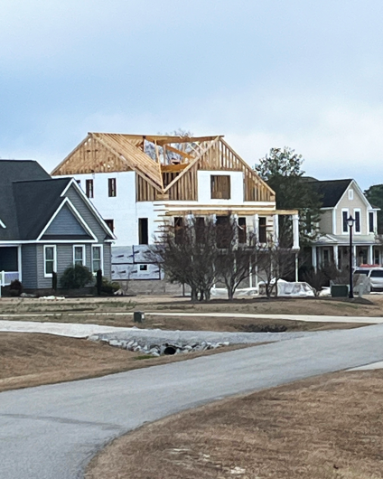 An in-progress house with walls but without a roof. We can see the wood skeleton.