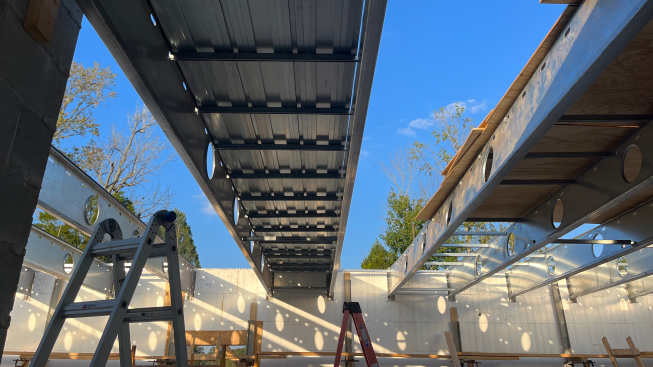 An in-progress raised concrete floor. The sunlight falls through the metal slats.