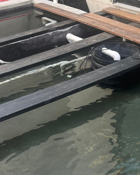 In-progress pond with wooden decking and metal reaching across the pond.