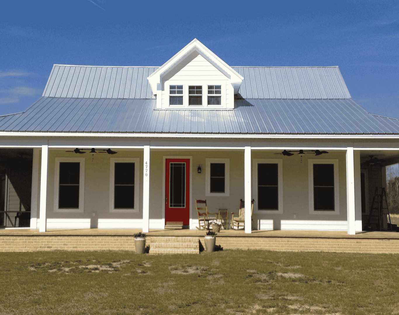 An energy-efficient South Carolina house with a porch, a metal roof, and a dormer window. Though it is not obvious on the surface, it has concrete walls beneath and is built using a variety of green building techniques.