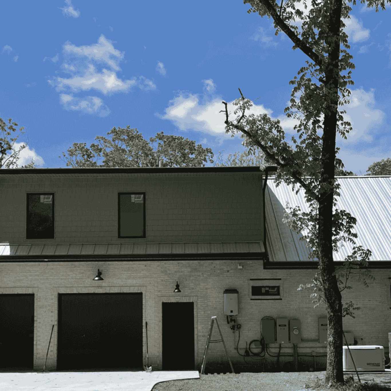 The back of a stone-and-vinyl house with a dormer and two-car garage. This type of energy-efficient house requires a reduced amount heating and cooling.