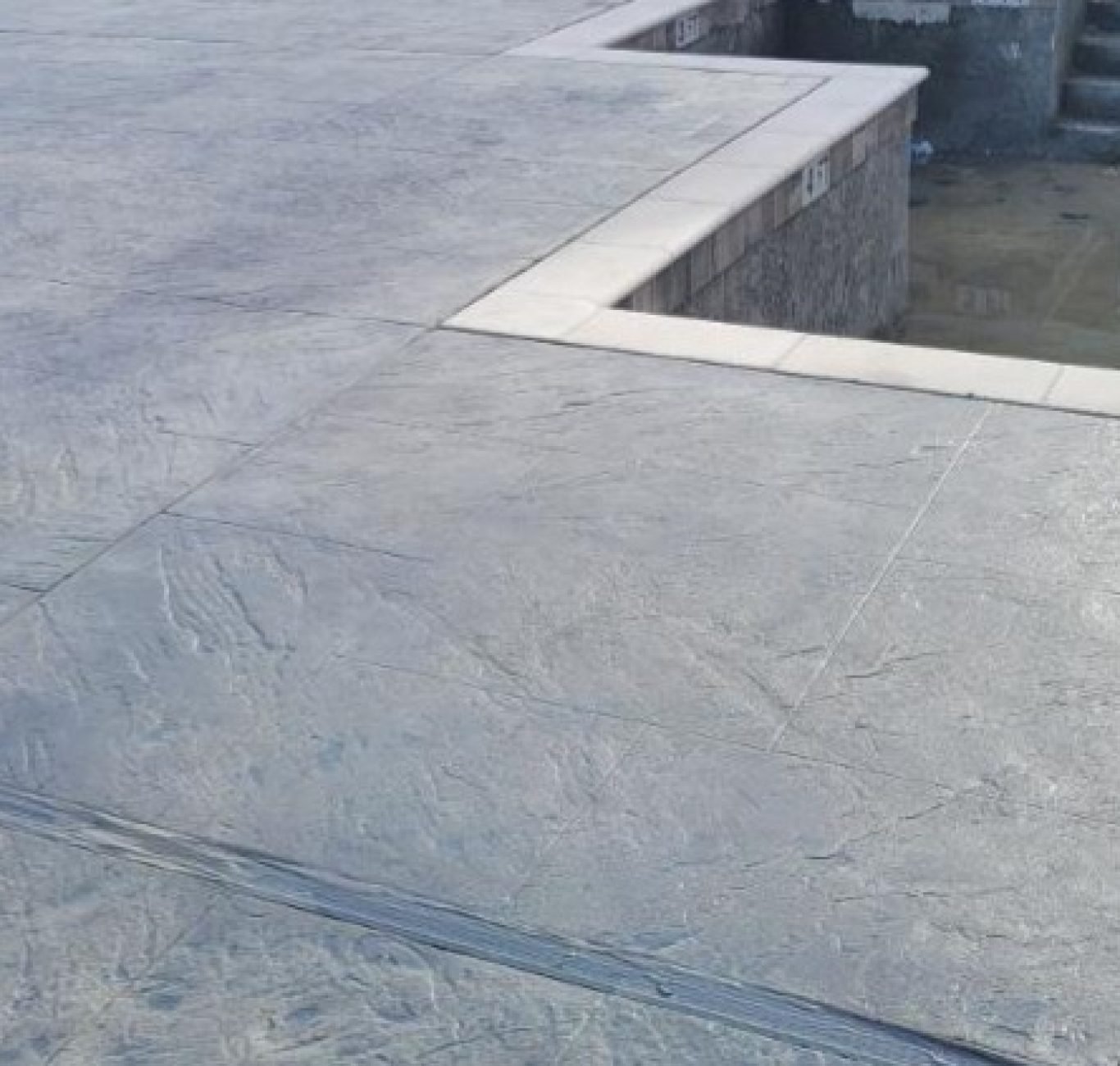 Decorative concrete stamped to look like stone surrounded a geometric pool