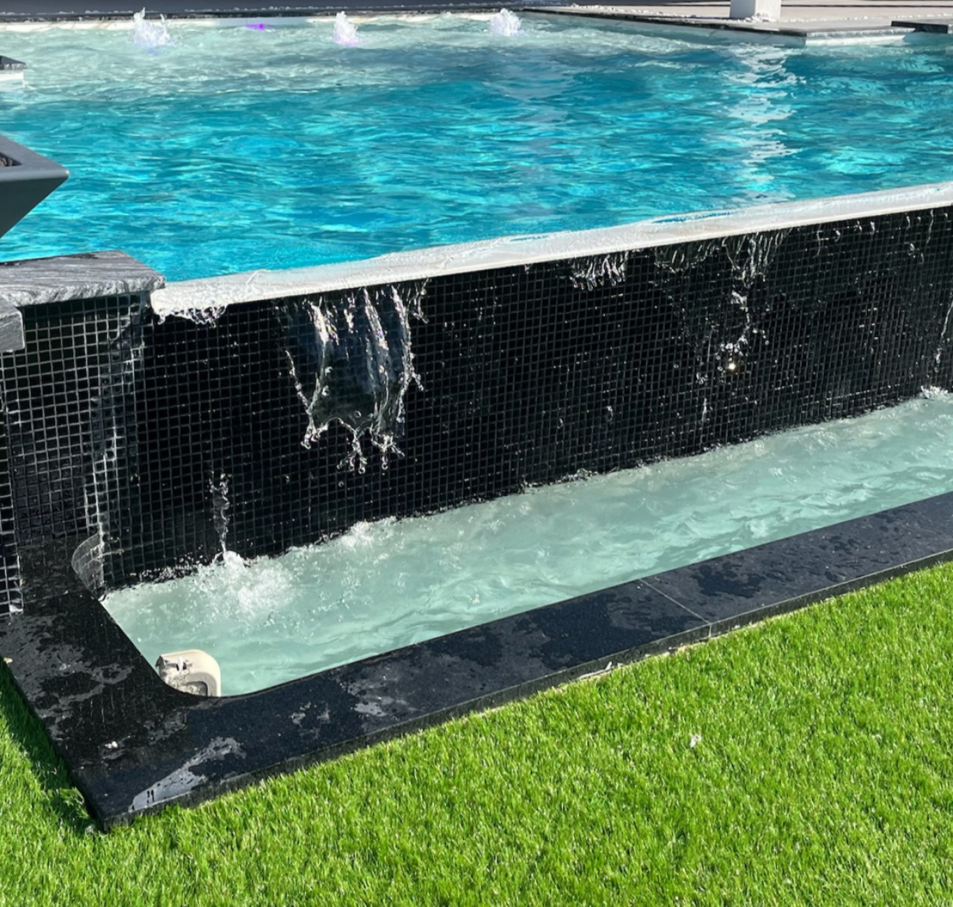 Gunite concrete pool. This pool is rectangular and has burners at the edges and little fountains on the center; the water pours over the edge like a waterfall