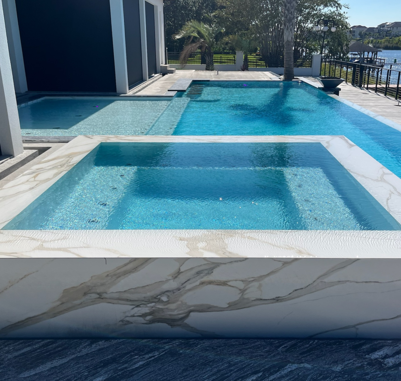 Custom rectangular technical concrete pool with rectangular hot tub. The concrete has a marble pattern.